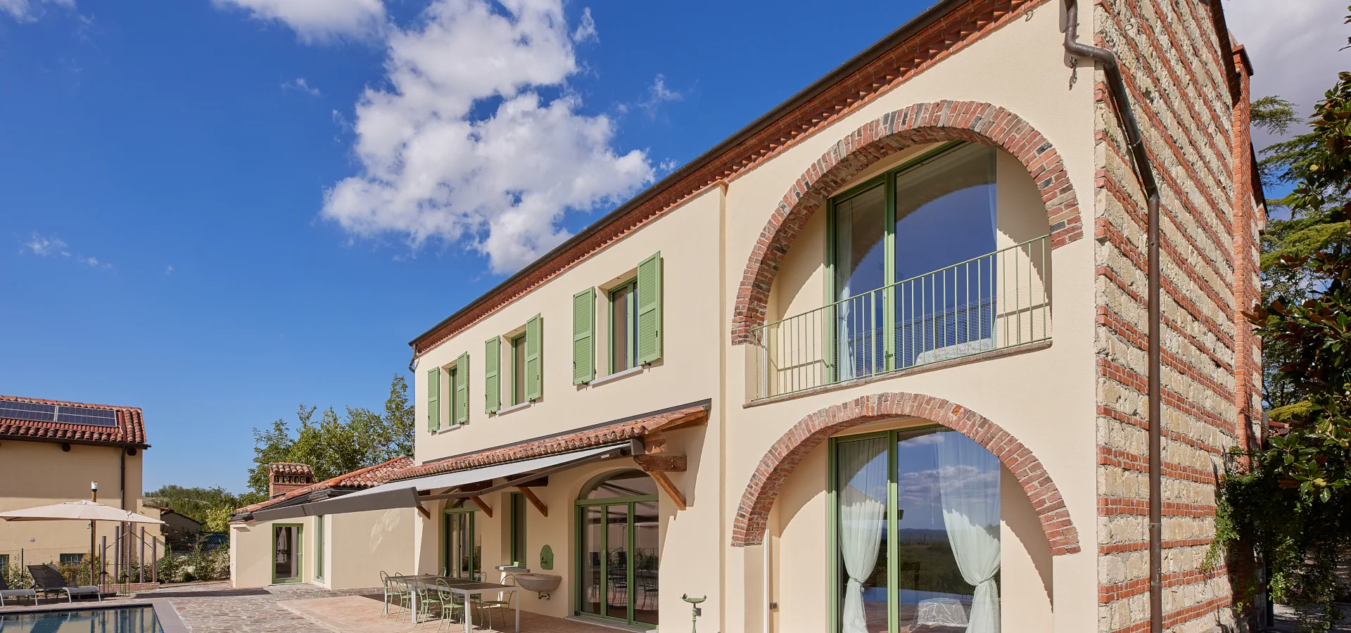 Villa Ozzano Monferrato - Vista delle facciate con dettagli in cotto naturale, di recupero e pietra da cantoni tipica del Monferrato, e zona pranzo esterna con tende ombreggianti automatiche - Design FSA Filippo Selis Architetto