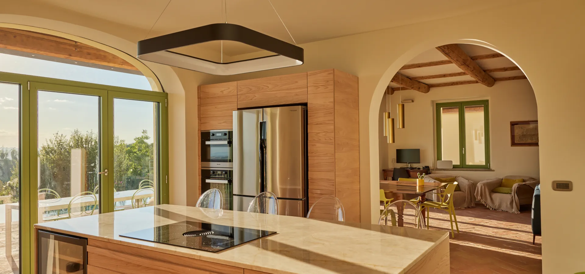 Villa Ozzano Monferrato - Vista al crepuscolo della cucina, realizzata artigianalmente su disegno originale in legno di olmo e quarzite naturale, semiaperta sul living - Design FSA Filippo Selis Architetto