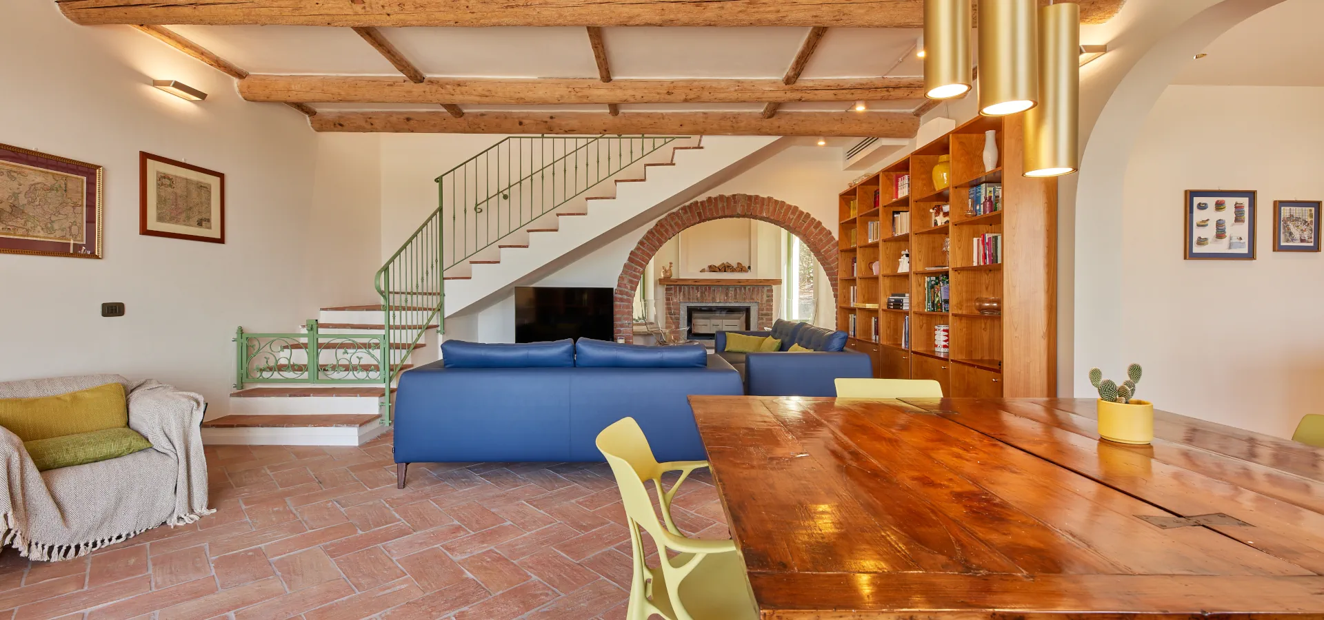 Villa Ozzano Monferrato - Living con pavimenti in cotto fatto a mano, travi in legno originali restaurate, tavolo pranzo d'epoca a libro in legno e vista del padiglione del caminetto attraverso l'antico arco in mattoni - Design FSA Filippo Selis Architetto
