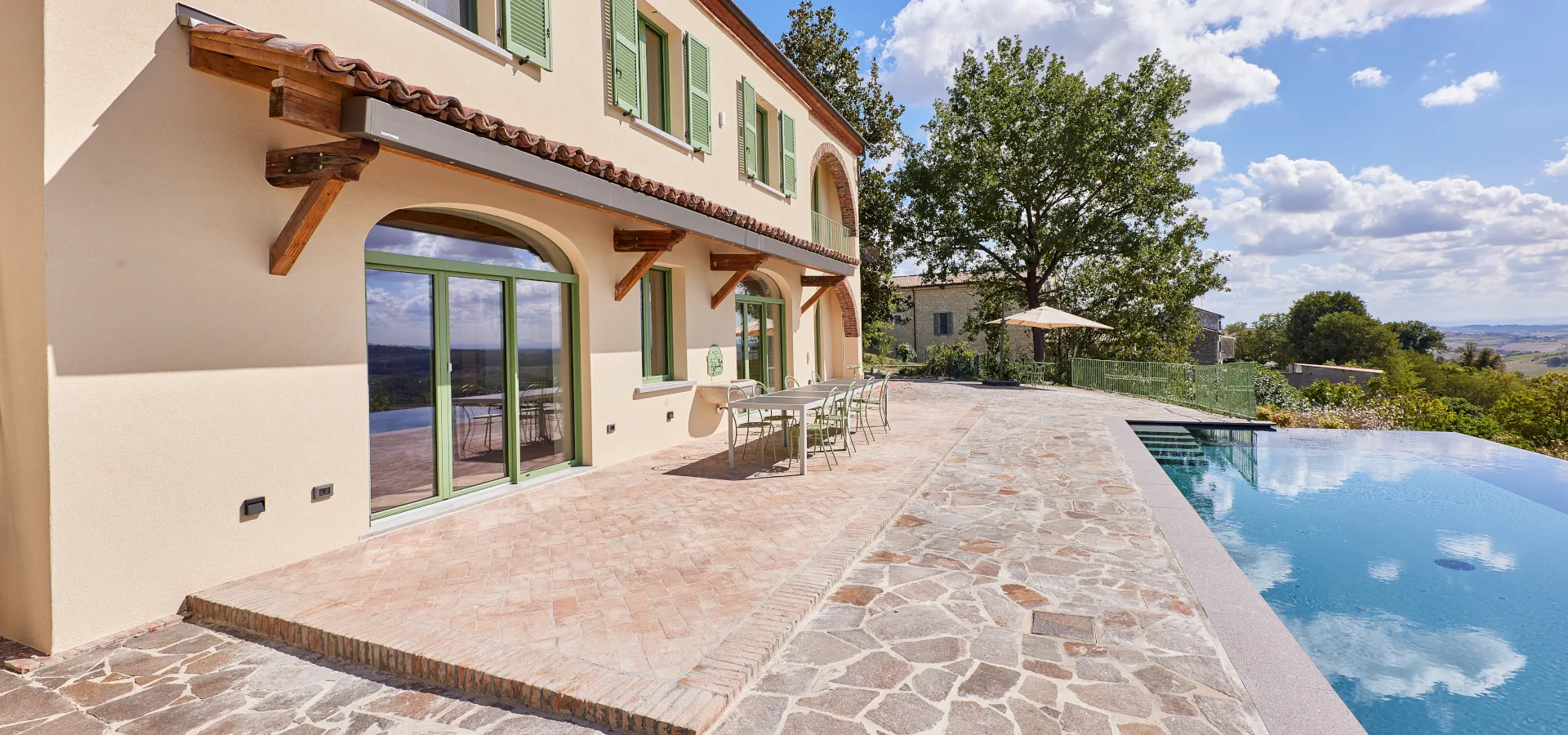 Villa Ozzano Monferrato - Vista della facciata con zona pranzo in cotto naturale, tettoia in coppi di recupero e piscina panoramica infinity - Design FSA Filippo Selis Architetto